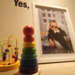 Montessori home setup with wooden stacking toy, bead maze and framed baby photo representing peaceful learning at Rumah Montessori Kecilku