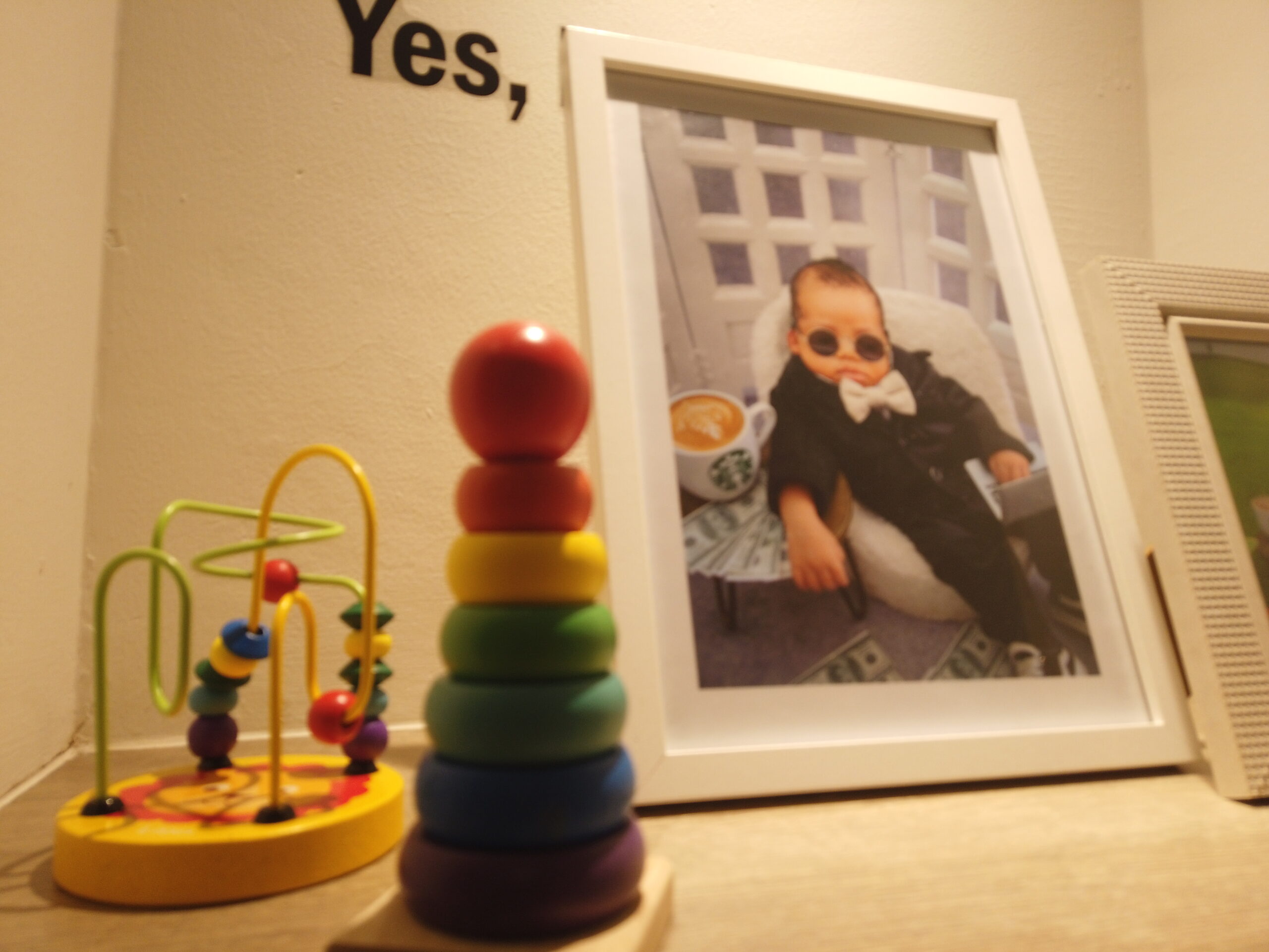 Montessori home setup with wooden stacking toy, bead maze and framed baby photo representing peaceful learning at Rumah Montessori Kecilku